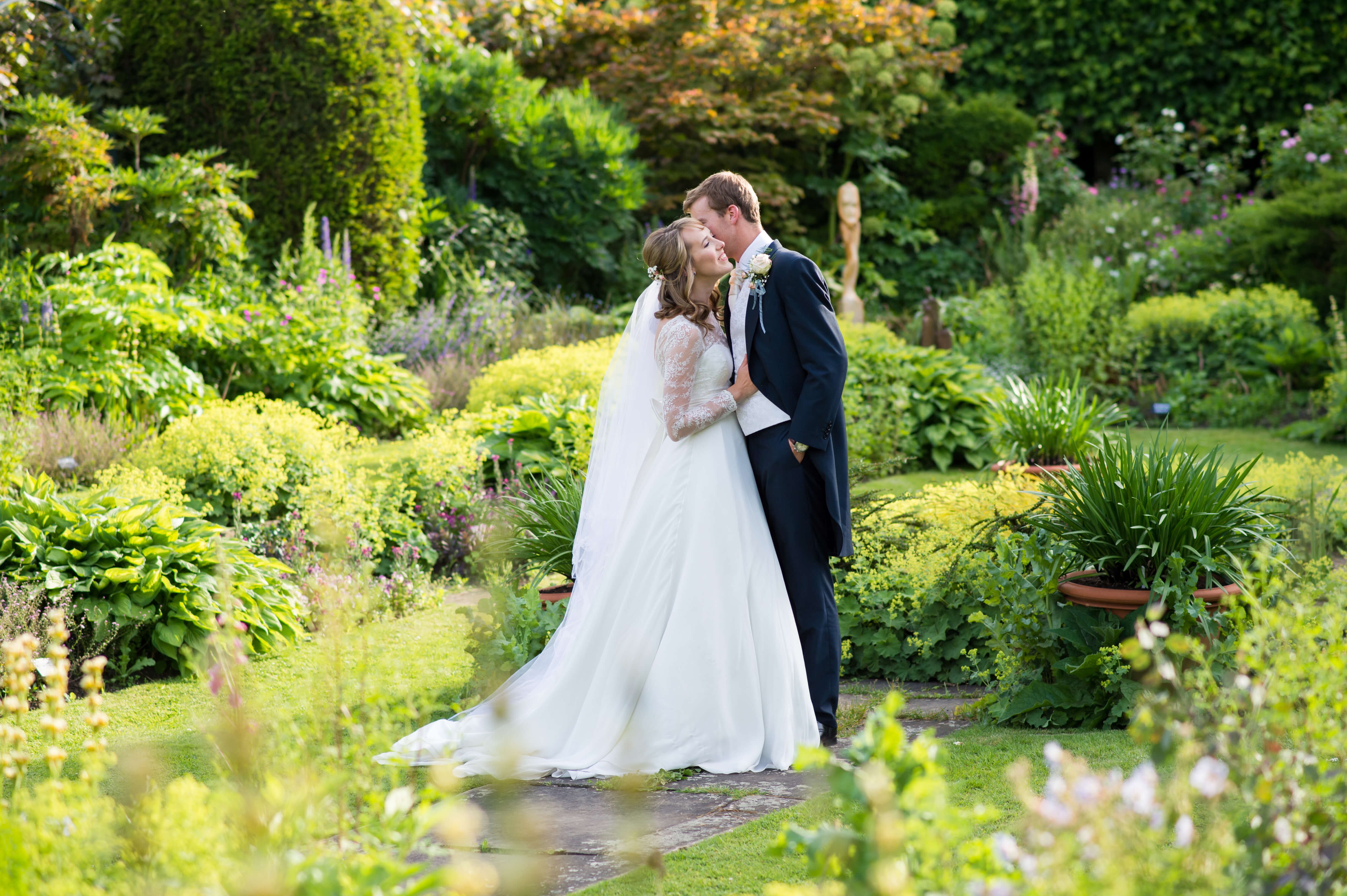 Bride and groom kissing in the walled gardens of chenies manor 